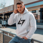 Model wearing Raverge men's white hoodie with the brand logo, showcasing sleek streetwear style.