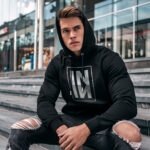 Raverge men's black hoodie IN worn by model mirrored typography minimal streetwear design