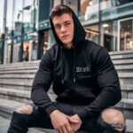 Model wearing Raverge men's black hoodie Wrath of the Heaven frontside bold title minimalist design