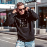 Model wearing Raverge men's black hoodie Deny Ordinary bold slogan confident streetwear look