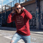 Model wearing Raverge men's red hoodie Deny Ordinary bold slogan confident streetwear look
