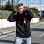 Model wearing Raverge men's black hoodie Verge of Breakthrough dynamic streetwear graphic frontside