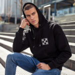 Model wearing Raverge Caution men's black hoodie with sci-fi caution graphic.
