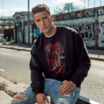 Model wearing men's black Challenge Everything sweatshirt with bold graphic text
