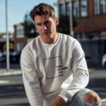 Model wearing the Raverge white Think Without the Box sweatshirt with unique typography design