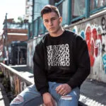 Model wearing men's black sweatshirt with spinning "Vertigo" text design