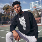 Model wearing Raverge men's Rise Up black sweatshirt with bold text design