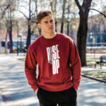 Model wearing Raverge men's Rise Up red sweatshirt with bold text design