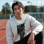 Model wearing Raverge men's Rise Up white sweatshirt with bold text design