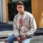 Model wearing Raverge men's Be Iconic white sweatshirt with bold text design