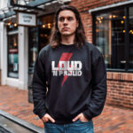 Man wearing Raverge men's Loud 'N Proud black sweatshirt with red lightning graphic and bold text.