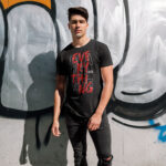 Black 'Challenge Everything' t-shirt with bold typography, streetwear style worn by a model.