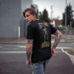 Model wearing black 'Storm Bringer' t-shirt featuring Poseidon statue graphic, showcasing powerful storm bringer design.