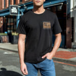 Model wearing black 'Storm Bringer' t-shirt featuring bold 'Lord of the Seas' and 'Holder of the Earth' text design.