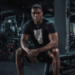 Model wearing the black Rise Up T-shirt with bold "Rise Up" typography and "No matter what" text beside it. A statement t-shirt for those who never back down.