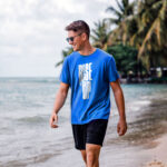 Model wearing the blue Rise Up T-shirt with bold "Rise Up" typography and "No matter what" text beside it. A statement t-shirt for those who never back down.