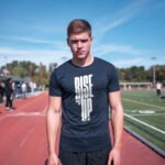 Model wearing the navy Rise Up T-shirt with bold "Rise Up" typography and "No matter what" text beside it. A statement t-shirt for those who never back down.