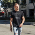 Male model showcasing black Raverge's 'Deny Ordinary' t-shirt in casual streetwear outfit