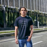 Male model showcasing navy Raverge's 'Deny Ordinary' t-shirt in casual streetwear outfit