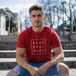 Male model showcasing red Raverge's 'Deny Ordinary' t-shirt in casual streetwear outfit
