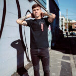 Male model showcasing the front side of Raverge's black 'Verge of Breakthrough' t-shirt