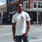 Male model showcasing the front side of Raverge's white 'Verge of Breakthrough' t-shirt