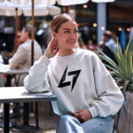 Woman wearing Raverge women's white sweatshirt with Raverge logo.
