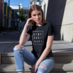 Model wearing Women’s Deny Ordinary black t-shirt with bold Raverge slogan