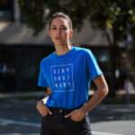 Model wearing Women’s Deny Ordinary blue t-shirt with bold Raverge slogan