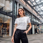 Model wearing Women’s Deny Ordinary white t-shirt with bold Raverge slogan