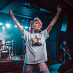 Model wearing Women’s Rock the World white t-shirt with bold text and red star graphic