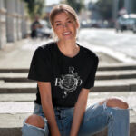 Model wearing Women’s Black Rose t-shirt with rose graphic and "Bloom Like a Rose" typography