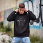 Model wearing Raverge Infinite Now men's black hoodie, inspired by the Eternal Now theory, featuring sleek typography on a black hoodie.