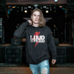 Model wearing Raverge men's black hoodie with Loud 'N Proud design, styled with rocker-inspired streetwear.
