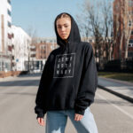Model wearing Raverge women's black hoodie with "Deny Ordinary" text.