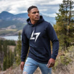 Model wearing Raverge men's navy hoodie with the brand logo, showcasing sleek streetwear style.
