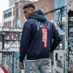Model wearing Raverge men's navy hoodie Verge of Breakthrough bold dynamic streetwear graphic backside view