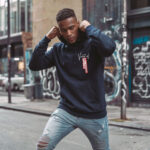 Model wearing Raverge men's navy hoodie Verge of Breakthrough dynamic streetwear graphic frontside