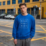 Model wearing men's Deny Ordinary blue sweatshirt with bold Raverge slogan