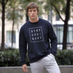 Model wearing men's Deny Ordinary navy sweatshirt with bold Raverge slogan