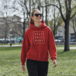 Model wearing Raverge women's red hoodie with "Deny Ordinary" text.