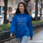 Model wearing Raverge women's blue hoodie with "Deny Ordinary" text.