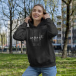Model wearing Raverge women's black hoodie with "Infinite Now" design inspired by the Eternal Now theory.